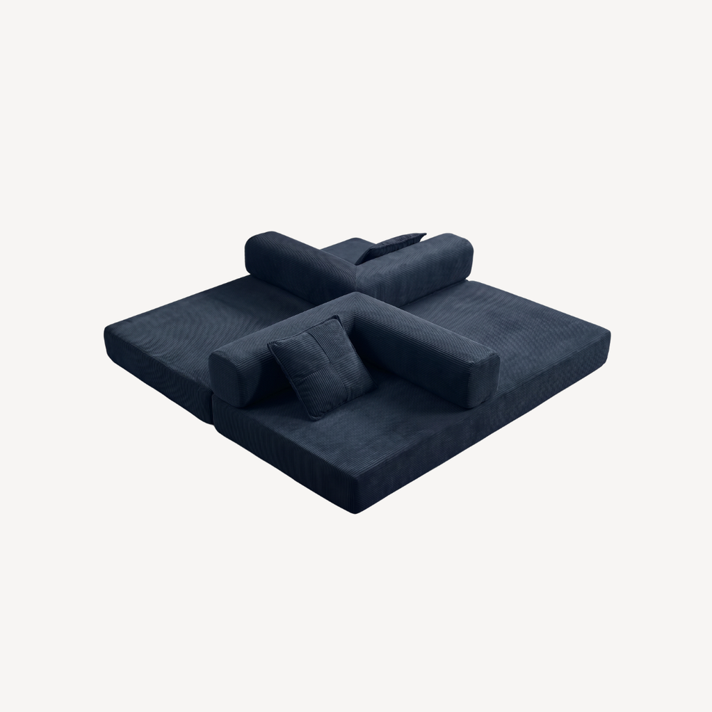Canapé convertible bleu foncé en velours côtelé, couchage étendu, coussins empilés.