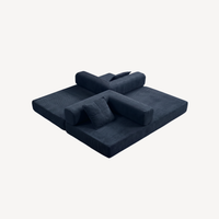 Canapé convertible bleu foncé en velours côtelé, couchage étendu, coussins empilés.