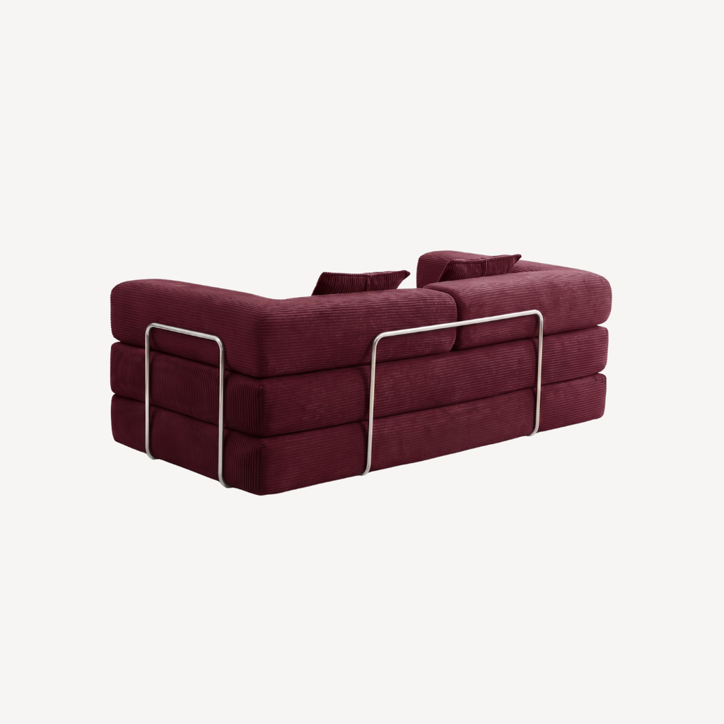 Canapé bordeaux en velours côtelé, assise déployée avec deux coussins décoratifs.