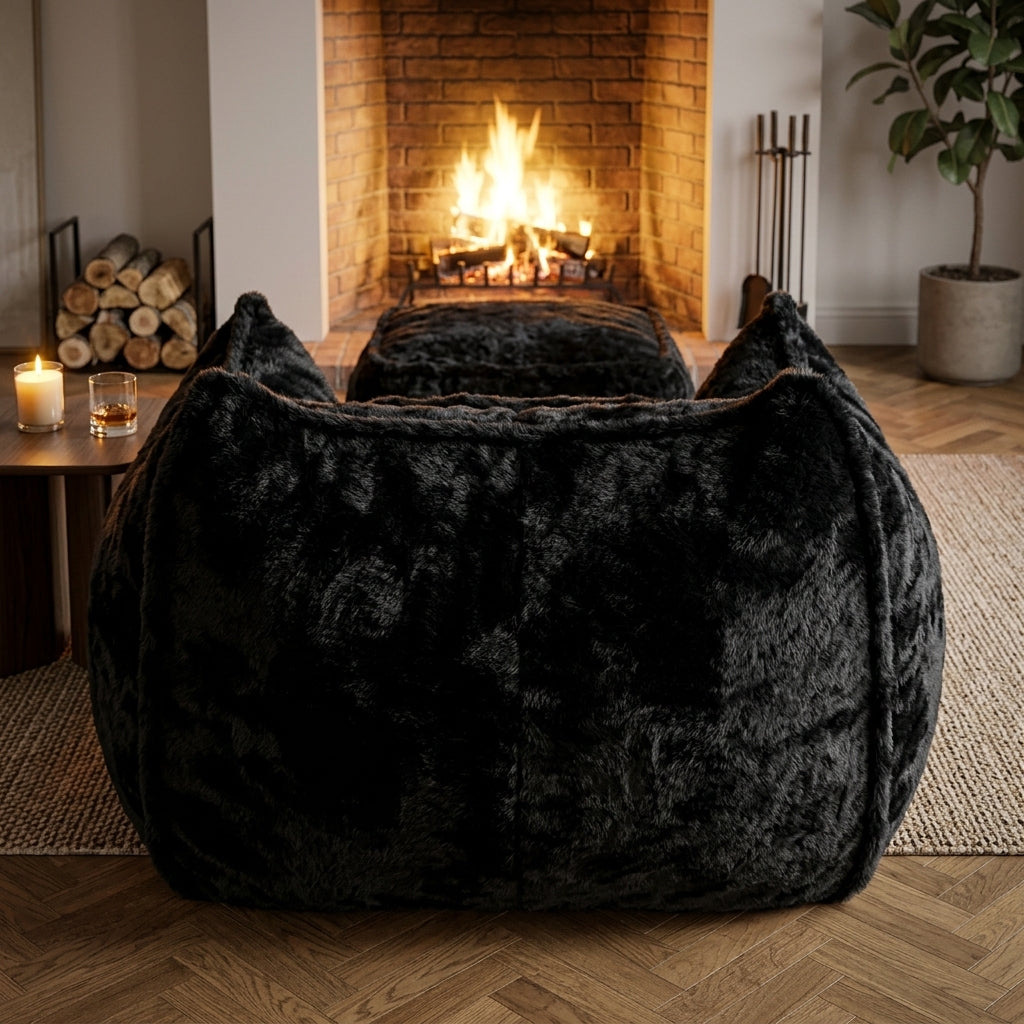 Fauteuil en fourrure noire très épaisse avec repose-pied, forme enveloppante.