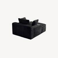 Fauteuil compressé 1 place en velours côtelé noir, vue latérale avec coussins d’appoint.